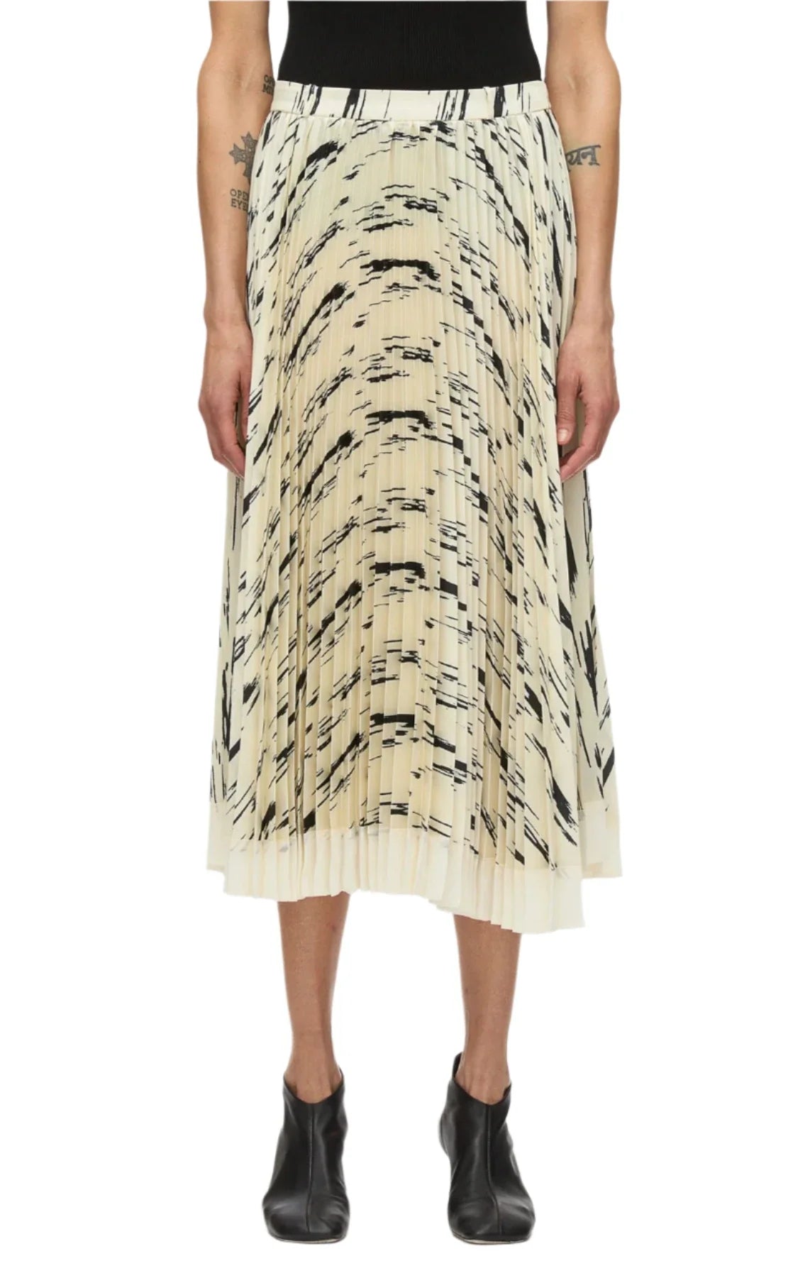 The person is wearing a 3.1 Phillip Lim Abstract Wood Grain Sunburst Pleated Skirt, paired with sleek black ankle boots.