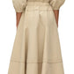 A person is seen wearing the 3.1 Phillip Lim V Neck Dress with Gathered Sleeves, a beige, long-sleeved dress that extends to the ankle and features belle sleeves and a gathered waist. The dress is crafted from Italian ottoman cotton, with the individual standing back to the camera.