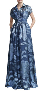 A woman wearing the Lela Rose Metallic Floral Fil Coupe Gown, a blue floral-patterned maxi dress with short sleeves, a collared neckline, and a fitted waistband enhanced with subtle metallic fil coupe detailing.