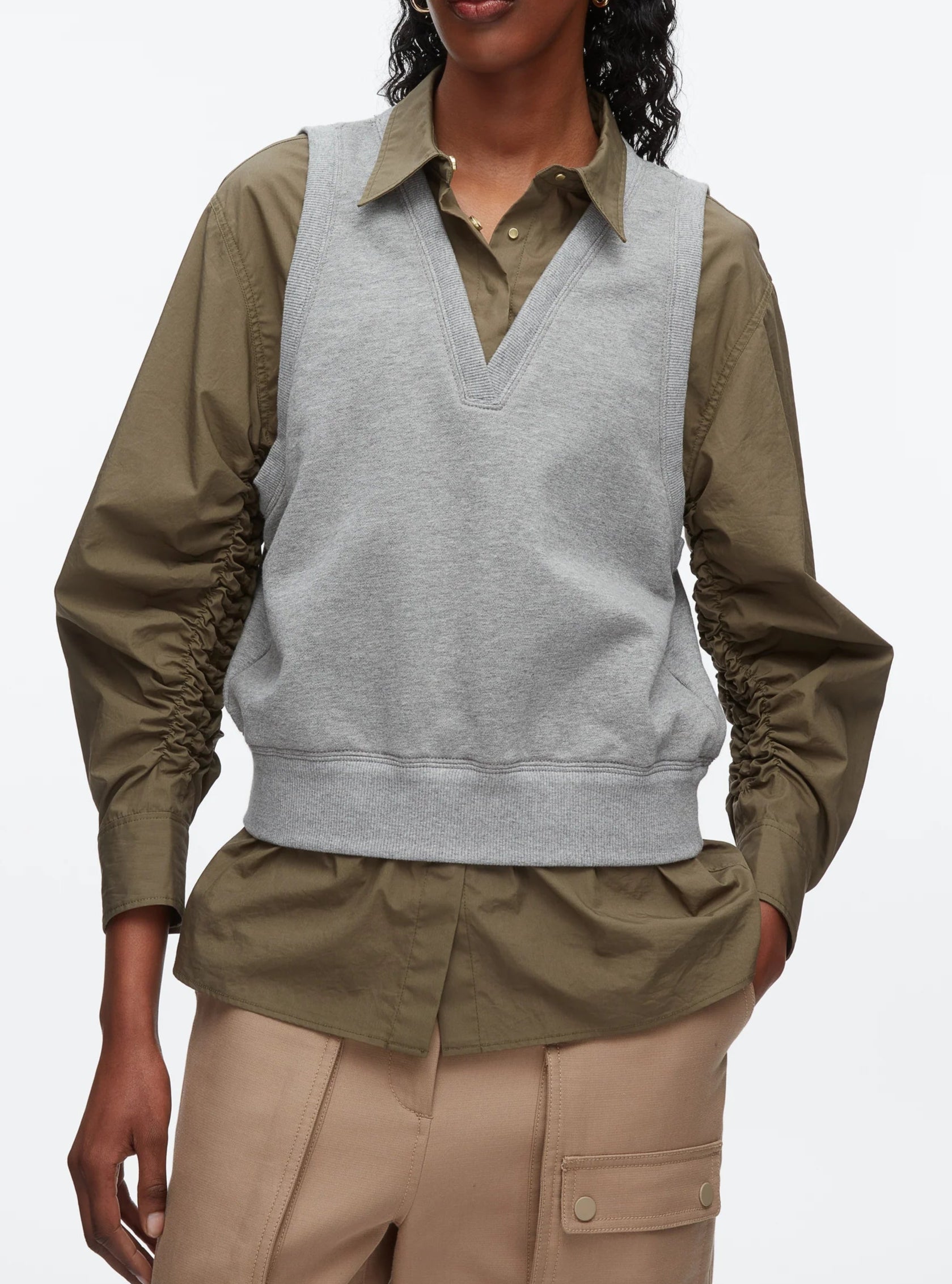 A person wears the 3.1 Phillip Lim Layered Vest Ruched Sleeve Shirt, styled with beige pants featuring large pockets.