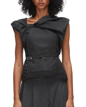 A woman wears the 3.1 Phillip Lim Sleeveless Draped Bow Top w Belt, featuring a sculptural neckline, paired with high-waisted gray trousers.