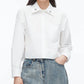 Wearing the 3.1 Phillip Lim Cropped Shirt with Embroidered Collar and light blue high-waisted jeans, this person stands with one hand in their pocket.