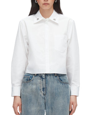 A person wears the 3.1 Phillip Lim Cropped Shirt with Embroidered Collar, featuring a chest pocket, styled with blue jeans.