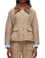A person wearing the 3.1 Phillip Lim Cropped Flounce Barn Jacket in beige with a brown corduroy collar, flap pockets, and matching beige pants, layered over a light blue checkered shirt.