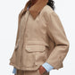 A person wearing the 3.1 Phillip Lim Cropped Flounce Barn Jacket featuring a brown corduroy collar, large front pockets, and button details, styled with a blue-and-white checked shirt.