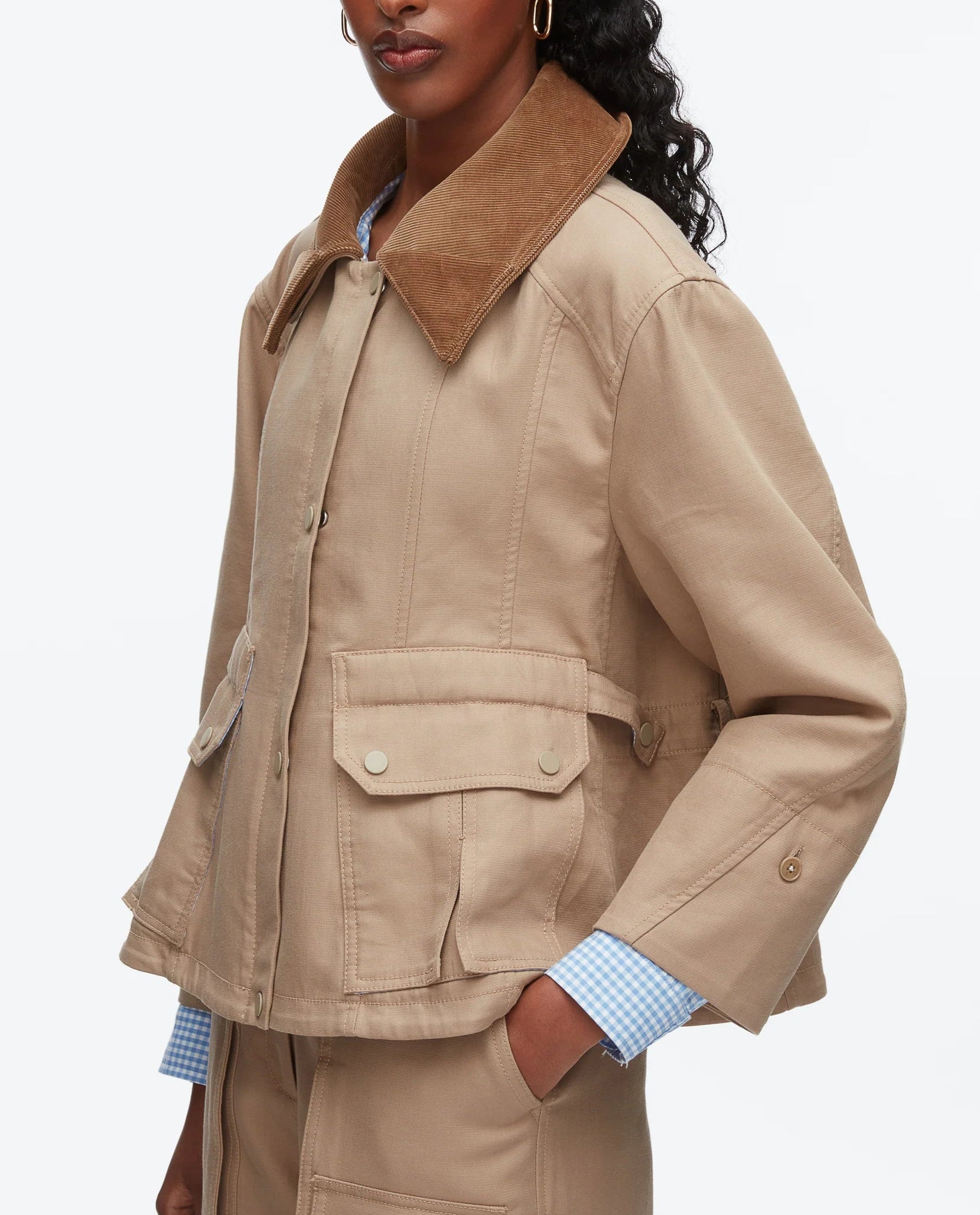 A person wearing the 3.1 Phillip Lim Cropped Flounce Barn Jacket featuring a brown corduroy collar, large front pockets, and button details, styled with a blue-and-white checked shirt.