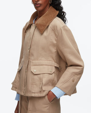 A person wearing the 3.1 Phillip Lim Cropped Flounce Barn Jacket featuring a brown corduroy collar, large front pockets, and button details, styled with a blue-and-white checked shirt.