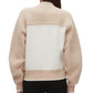 Someone is seen from the back wearing the 3.1 Phillip Lim Raglan Zip Cardigan in beige and white color block with long sleeves, paired with black pants.
