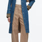 A person wears the 3.1 Phillip Lim Denim Combo Trench over a white top, paired with beige high-waisted pants with rolled cuffs and brown shoes.