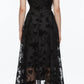 A person faces away, wearing the 3.1 Phillip Lim Flocked Organza Sleeveless Midi Dress Combo and black boots—a sheer floral design that defines modern occasion dressing.