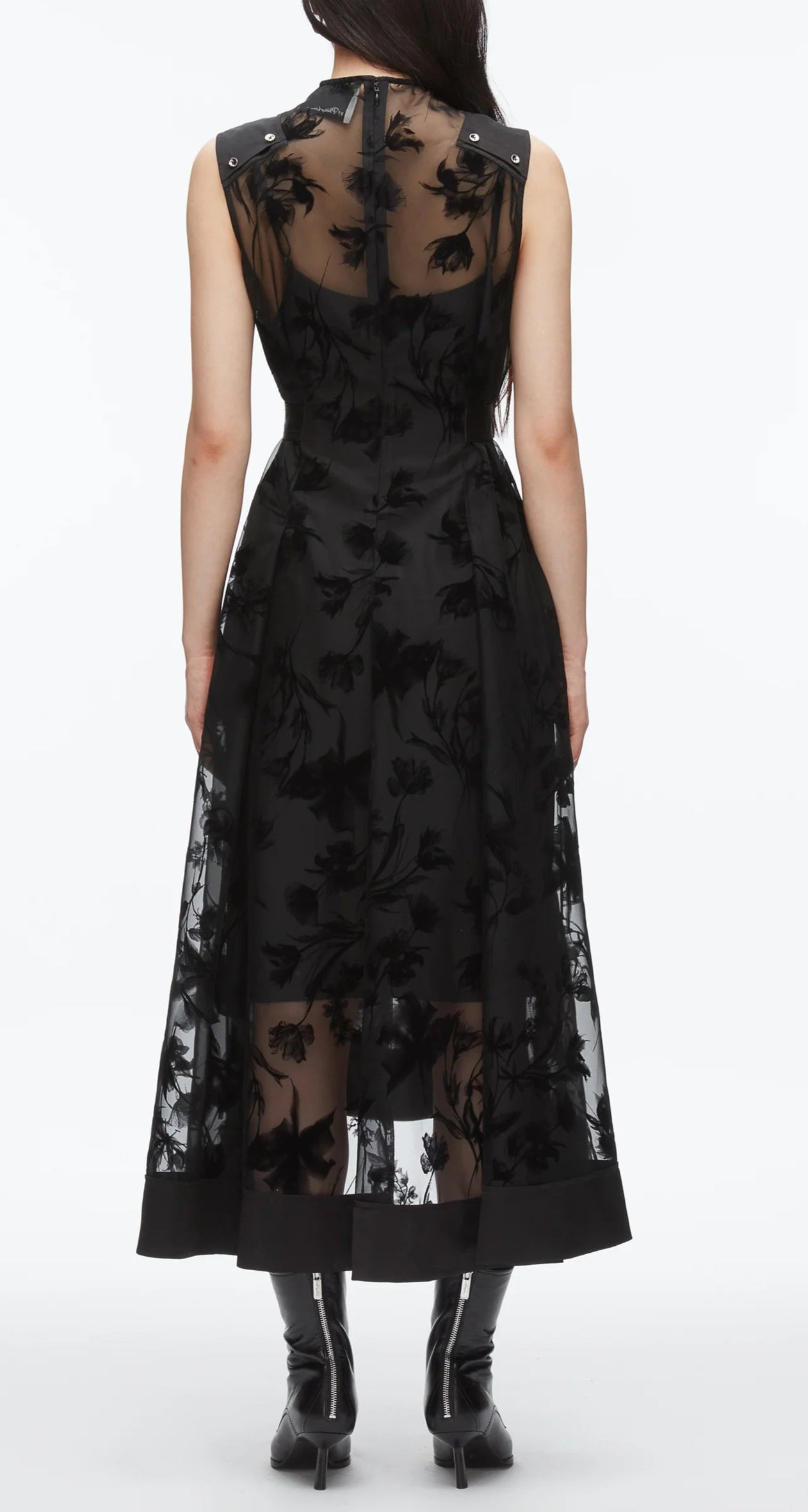 A person faces away, wearing the 3.1 Phillip Lim Flocked Organza Sleeveless Midi Dress Combo and black boots—a sheer floral design that defines modern occasion dressing.