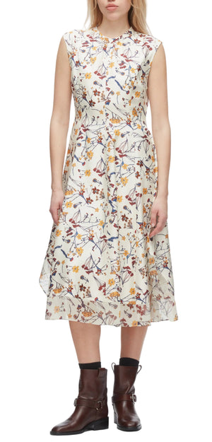 A woman wears the 3.1 Phillip Lim Bliss Floral Sleeveless Dress with a chiffon hem, featuring a vibrant floral pattern, paired with brown ankle boots.