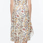 A woman faces away, wearing the 3.1 Phillip Lim Bliss Floral Sleeveless Dress with a chiffon hem, styled with brown ankle boots.