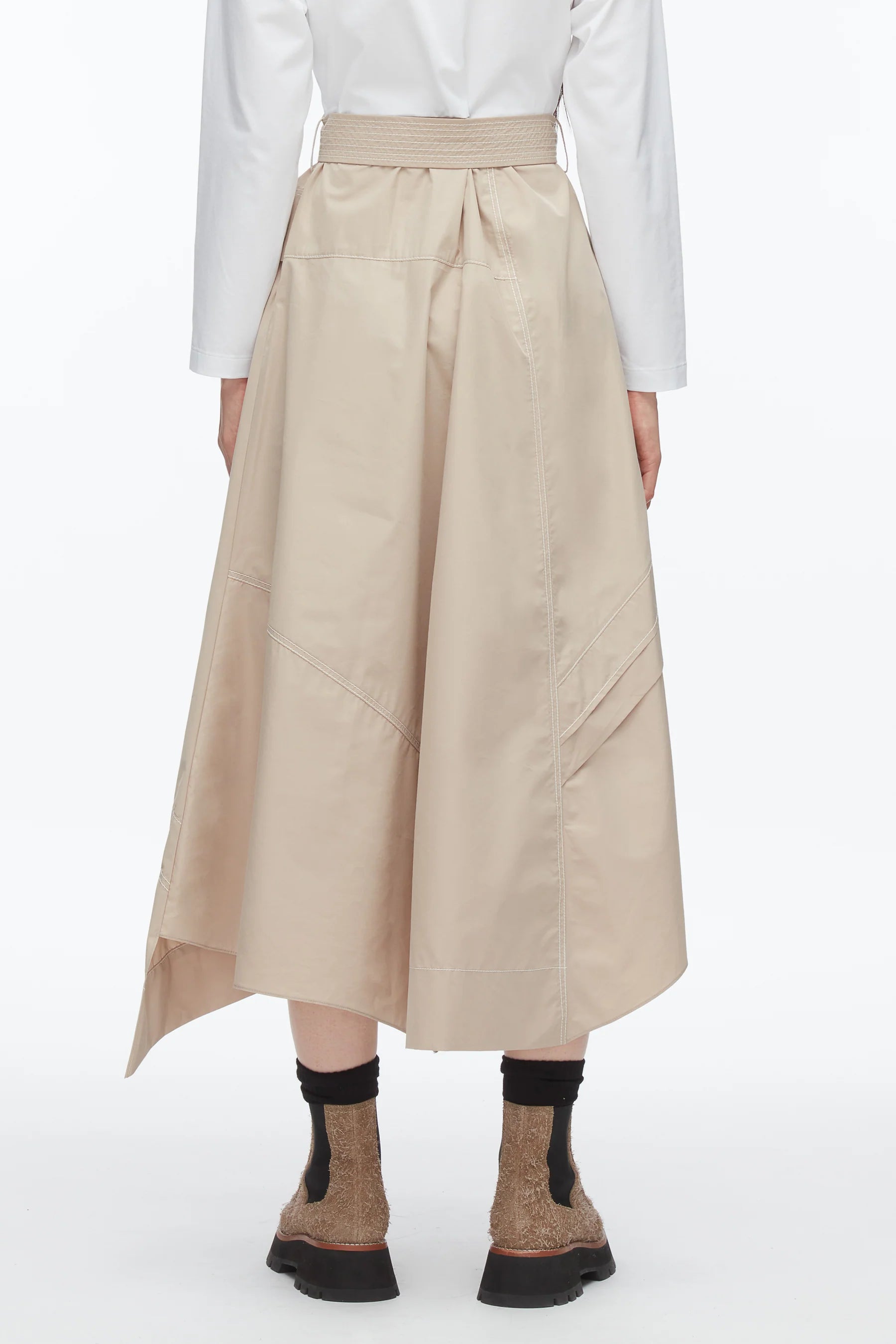 A person shown from the back against a plain background wears the 3.1 Phillip Lim Combo T-Shirt Dress, featuring beige cotton poplin with asymmetric draping, paired with brown socks and black shoes.