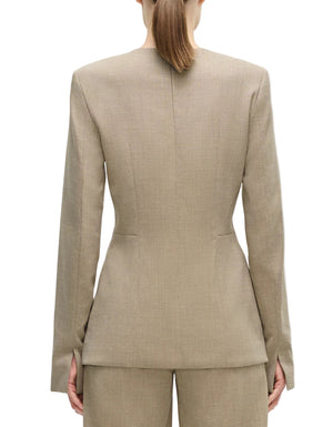 A person faces away from the camera, wearing the Adam Lippes Noa Top—a beige tailored blazer with removable shoulder pads—paired with matching trousers, set against a white background.