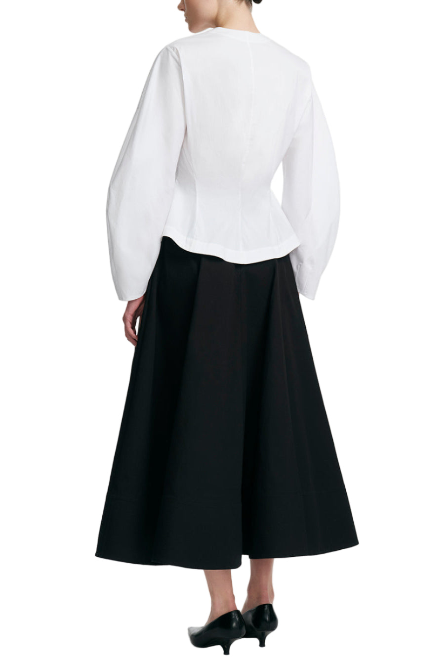 A person wearing the Lela Rose Button Front Peplum Top and a black midi skirt stands facing away, with black low-heeled shoes visible.