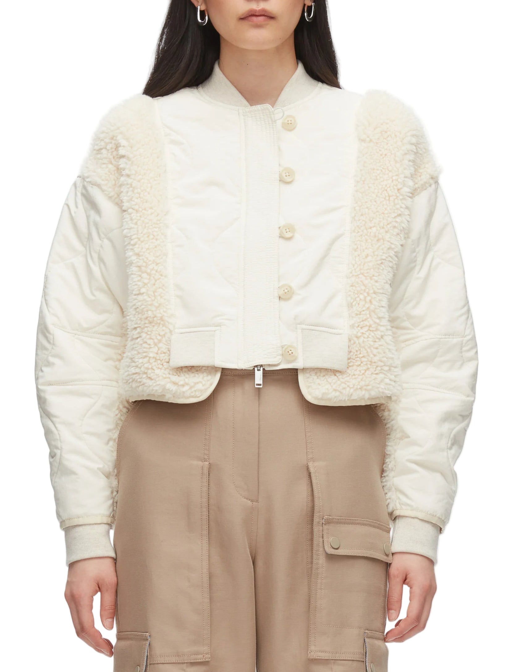 A person models the 3.1 Phillip Lim Cropped Sherpa Combo Bomber with beige cargo pants. Their long, dark hair flows freely as they face forward, effortlessly showcasing this stylish quilted jacket with faux shearling trim.