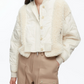 A woman wears the 3.1 Phillip Lim Cropped Sherpa Combo Bomber over a white top and high-waisted beige cargo pants.