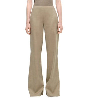 A person wearing the Adam Lippes Lamy Pant—high-waisted, wide-leg tailored trousers in beige Italian wool with a fitted waist—stands against a plain background.