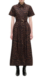 A person wears the Adam Lippes Leighton Dress in brown leopard print cotton poplin with short sleeves, collared neckline, and belted waist, paired with black ankle boots, set against a white background.