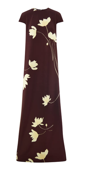 The Augusta Fluid Crepe Gown by Lela Rose is a sleeveless, floor-length maroon dress with a straight silhouette and an elegant cream large-blossom floral print.