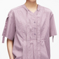 A person wearing the 3.1 Phillip Lim Short Sleeve Striped Tie Neck Blouse in light purple, featuring classic shirting details and a V-neck placket collar, shown from shoulders to mid-torso.