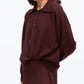 A woman wearing the 3.1 Phillip Lim Ultrafine Merino Polo Midi Dress in a loose-fitting, long-sleeve style and deep burgundy hue, standing against a plain white background.
