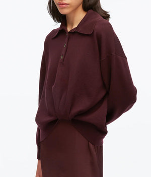 A woman wearing the 3.1 Phillip Lim Ultrafine Merino Polo Midi Dress in a loose-fitting, long-sleeve style and deep burgundy hue, standing against a plain white background.