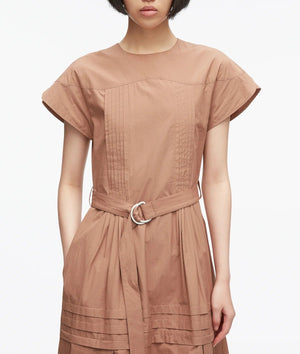 A woman stands against a plain white background wearing the 3.1 Phillip Lim Pleated Poplin Tulip Sleeves Midi Dress, featuring short tulip sleeves, pintuck detailing, and a self belt at the waist in light brown cotton poplin.