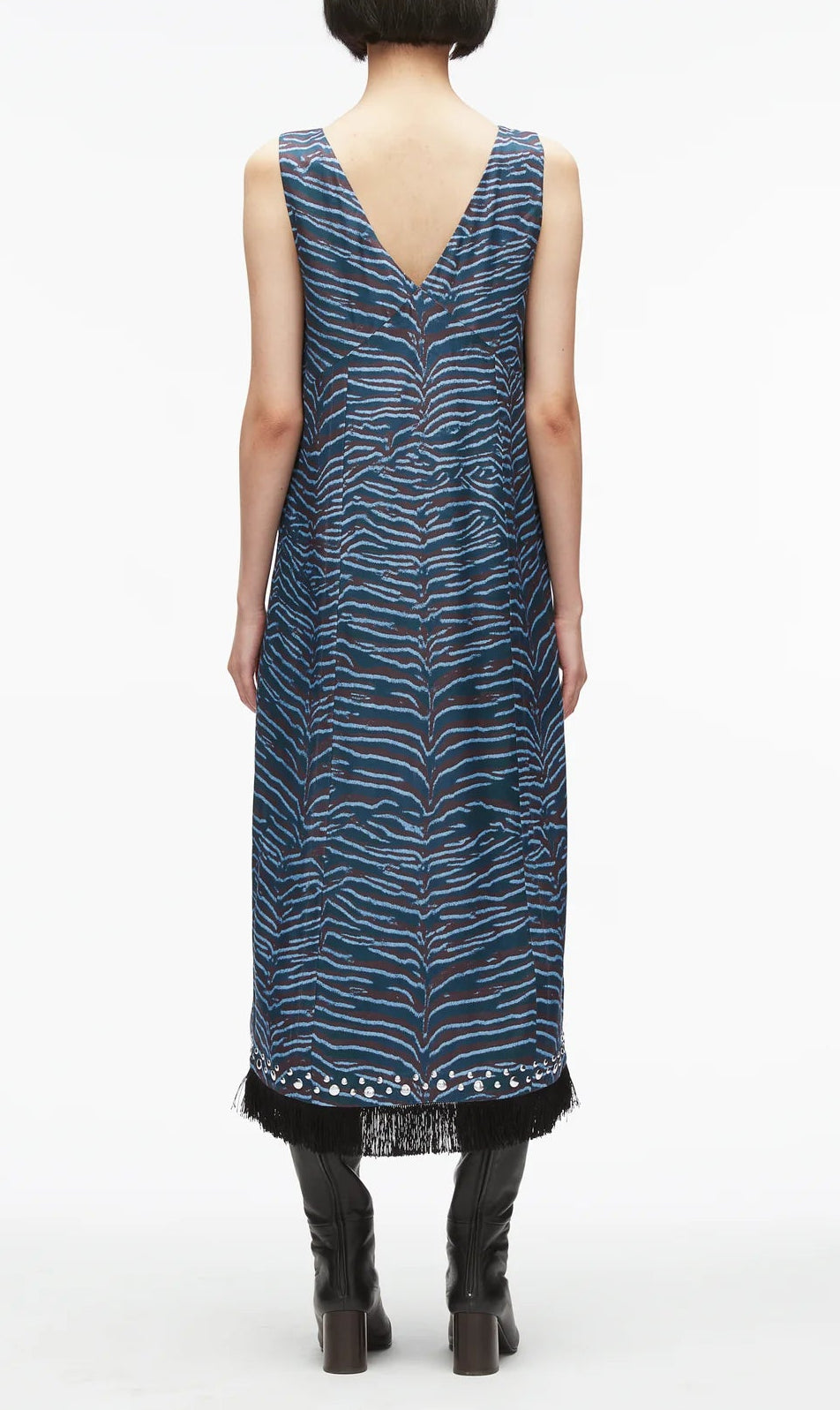A person with short dark hair is wearing the 3.1 Phillip Lim Tiger Print Studded Midi Dress, paired with black boots and standing against a white background.