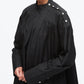 A person wearing the 3.1 Phillip Lim Long Sleeve Poplin Mini Dress, a loose-fitting black dress with white snap buttons on the shoulder and cuff and utilitarian detailing, stands against a white background.