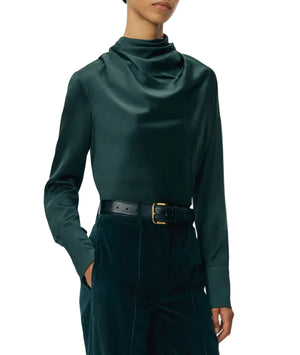 Person wearing the Blaine Silk Cashmere Top by Adam Lippes in dark green, tucked into high-waisted dark pants with a black belt, face partially out of frame.