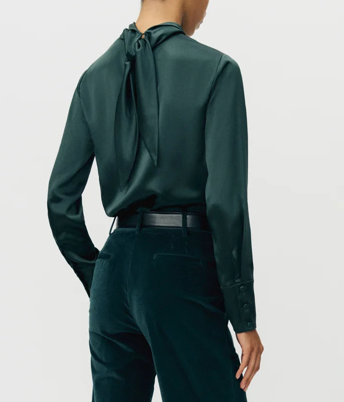 Person wearing the Adam Lippes Blaine Silk Cashmere Top in hunter green with tied neck detail and matching velvet pants, seen from the back.