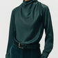 Model in the Adam Lippes Blaine Silk Cashmere Top in hunter green, styled with dark high-waisted pants and a black belt featuring a gold buckle.