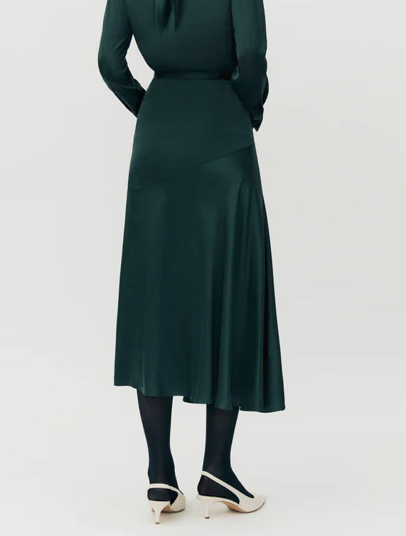 A person wearing the Adam Lippes Tess Silk Charmeuse Skirt with black tights and cream heels, standing against a plain light background.