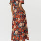 Person shown from the back wearing the Leighton Dress by Adam Lippes in vibrant floral Italian cotton poplin, paired with cream heeled boots.