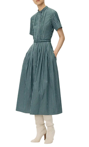 A person wearing the Doron Stripe Shirting Dress by Adam Lippes, a teal and white striped, short-sleeve, midi organic cotton dress with white knee-high boots.