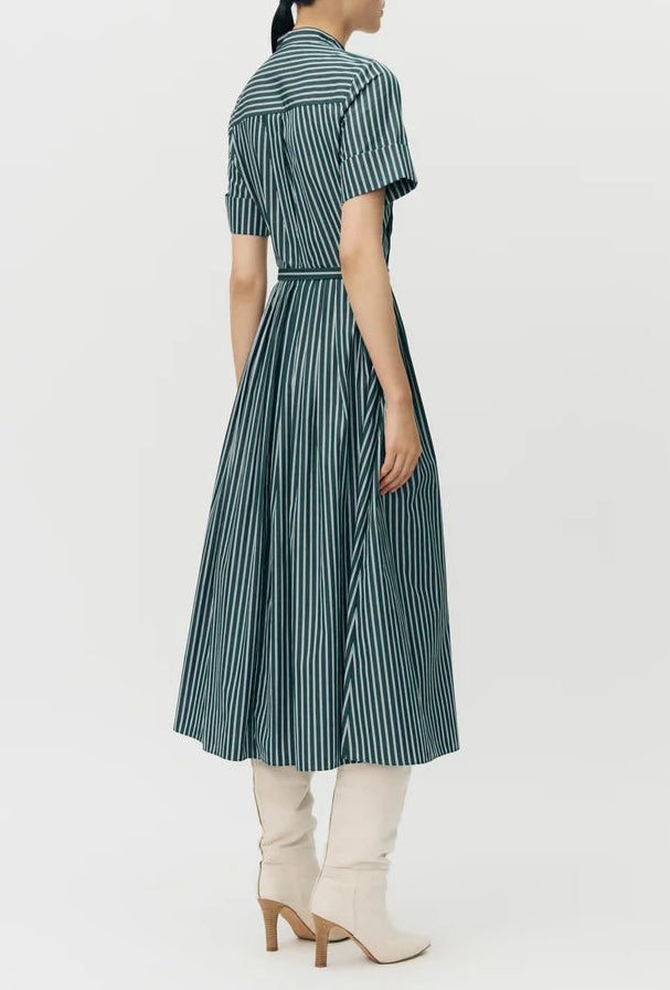 Woman with back turned wears the Doron Stripe Shirting Dress by Adam Lippes and knee-high white heeled boots against a plain background.