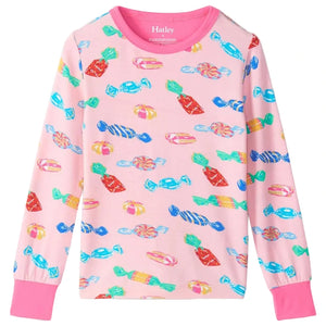 The Hatley Girls’ Delicious Candies Bamboo Pajama Set features a pink long-sleeve children’s shirt adorned with a colorful candy print, showcasing various wrapped sweets in blue, red, and yellow, and finished with pink cuffs—ideal for cozy bedtime wear.