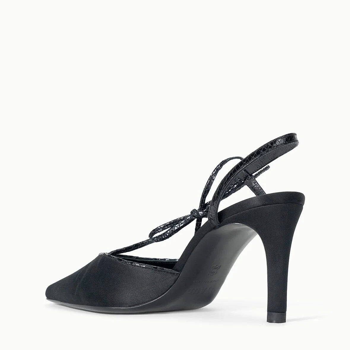 The Staud Inez Heel is a black slingback shoe with a pointed toe, a thin ankle strap, and a stiletto heel. It features an elastic back strap for added comfort and is photographed from the side against a plain white background.