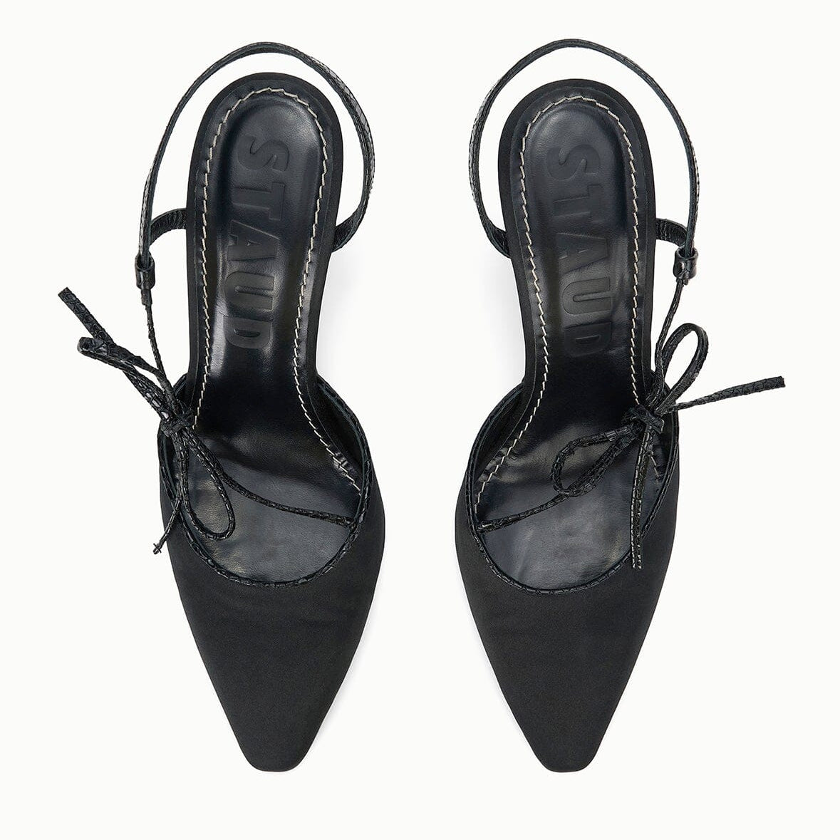 A pair of Staud Inez Heel black pointed-toe slingback shoes featuring thin elastic back straps and side bow detailing, viewed from above on a white background. This stylish design adds a chic touch to your ensemble, capturing the timeless elegance of the Inez Heel by Staud.