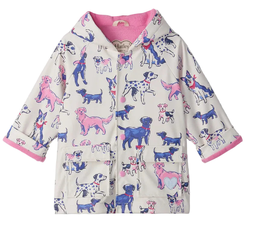 The Hatley Baby Girls’ and Girls’ Little Pups Rain Coat features a charming print of blue, pink, and purple cartoon dogs on a white background, a soft terry towelling lining, and two front pockets.