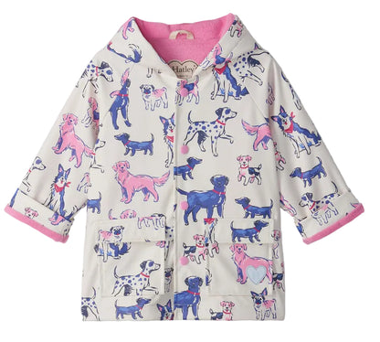 The Hatley Baby Girls’ and Girls’ Little Pups Rain Coat features a charming print of blue, pink, and purple cartoon dogs on a white background, a soft terry towelling lining, and two front pockets.