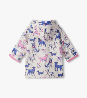 The Hatley Baby Girls’ and Girls’ Little Pups Rain Coat is a children’s hooded rain jacket with a soft terry towelling lining for added comfort. It features playful pink trim and an all-over print of blue, purple, and pink cartoon dogs on a white background.