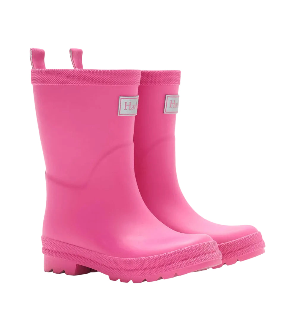 A pair of Hatley Girls’ Pink Yarrow Matte Rain Boots with textured soles and pull tabs at the top, positioned side by side on a white background.