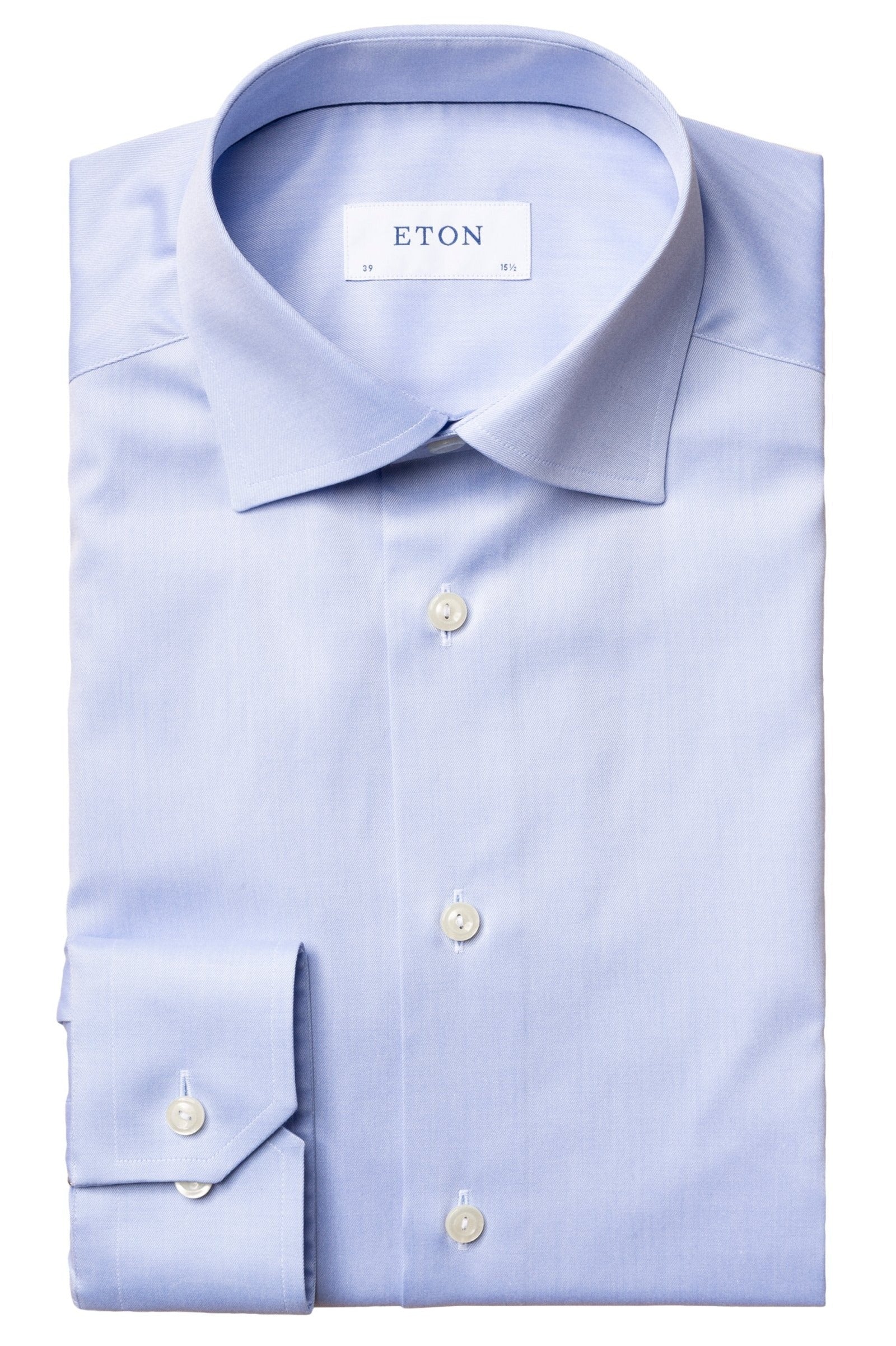 The folded Eton Light Blue Signature Twill Shirt, Slim Fit, showcases Eton's renowned twill fabric with a label on the inside collar. This classic piece is adorned with white buttons and a timeless collar, exemplifying wrinkle-free elegance.