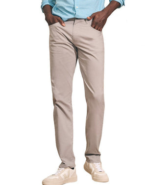 A person wearing a blue checkered shirt, Faherty's Movement Five Pocket Pants with 4-way stretch for comfort, and white sneakers.