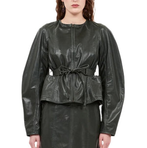 Person wearing a shiny long-sleeve Ulla Johnson Aidan Jacket in jasper green, featuring a front zipper and waist tie detail, reminiscent of the sleek style associated with the brand.