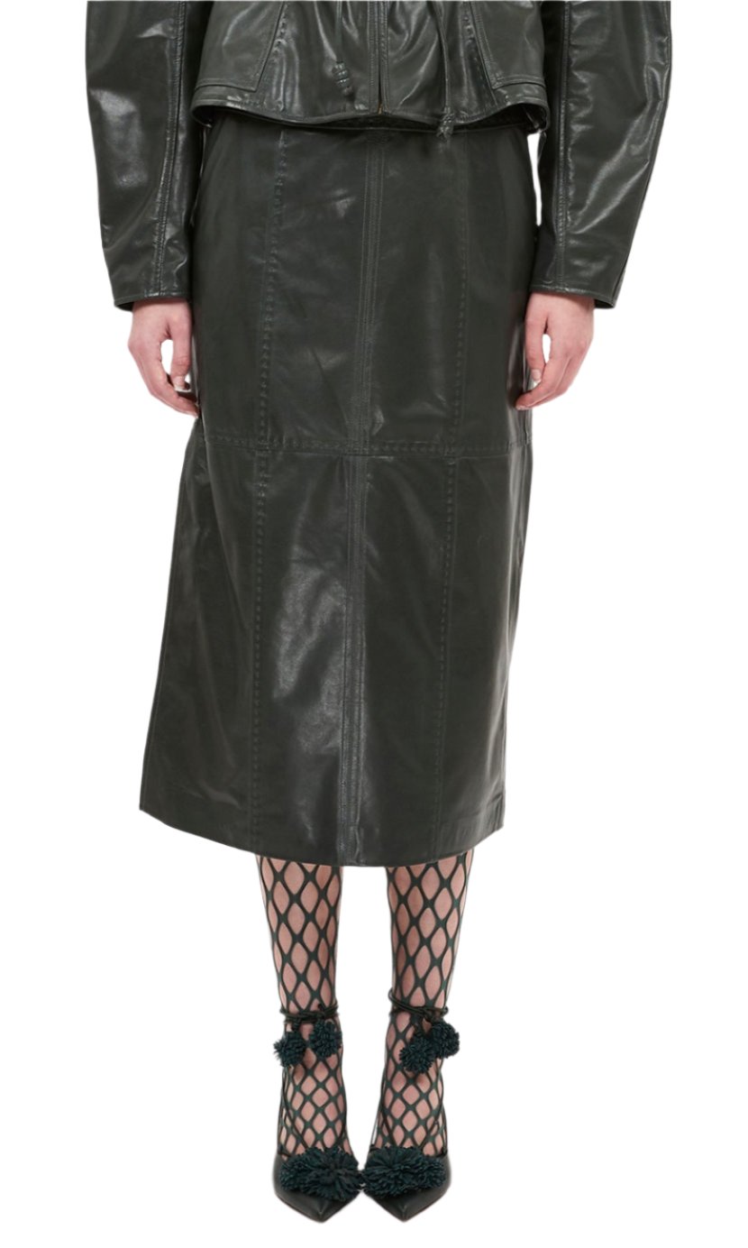 A person wearing a jasper green lambskin leather jacket paired with a Ulla Johnson Enid Skirt, fishnet stockings, and green high heels. Only the lower half of the body is visible.