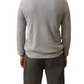 A person stands with their back to the camera, wearing the Faherty Sunwashed Crewneck Sweater in light gray textured cotton yarn and dark gray pants against a white background.